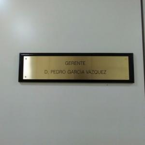 Placa de latón grabada en bajo relieve y patina de tintasobre peana o metopa de madera. Universidad de Sevilla.