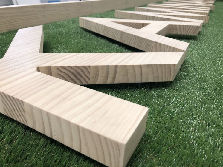 Letras corpóreas en madera natural con cesped artifical e iluminados con led para Kaminature en Sevilla.