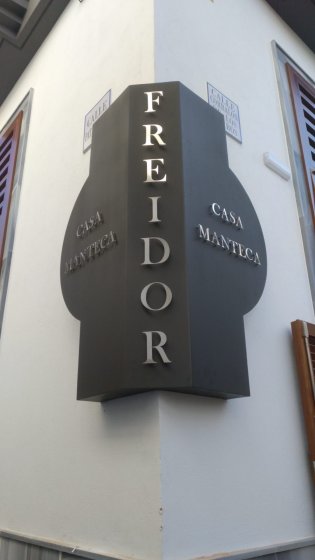 R&oacute;tulo corp&oacute;reo en esquina con letras recortadas en acero inoxidable. Casa Manteca en C&aacute;diz.