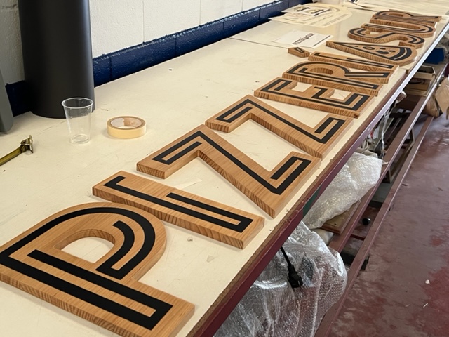 Letras corpóreas en madera recortado y frente rotulado en vinilo. 