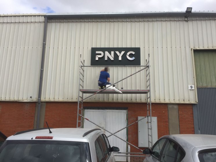 R&oacute;tulo corp&oacute;reo en acero inoxidable sobre bandeja de composite para PNYC en Sevilla.