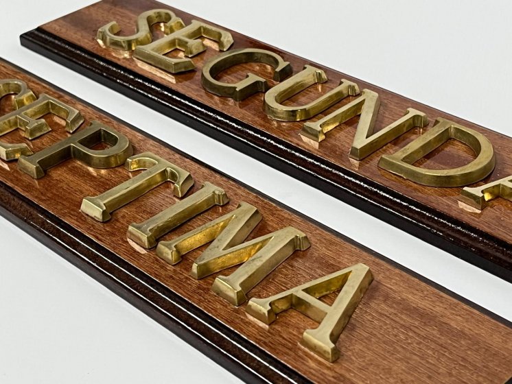 Rótulo señalizador con texto en latón fundido con base de madera.