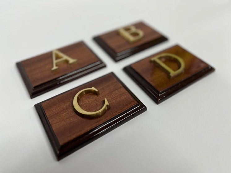 Rótulo señalizador con texto en latón fundido con base de madera.