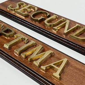 Rótulo señalizador con texto en latón fundido con base de madera.