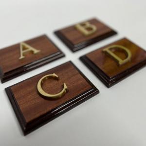 Rótulo señalizador con texto en latón fundido con base de madera.